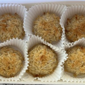 six plain coconut macaroons in individual paper cups in a white bakery box